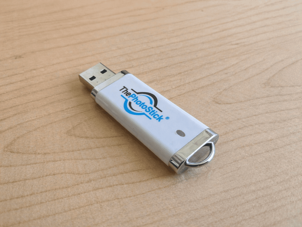 PhotoStick review close-up: Silver 128GB device unboxed on a wooden desk.