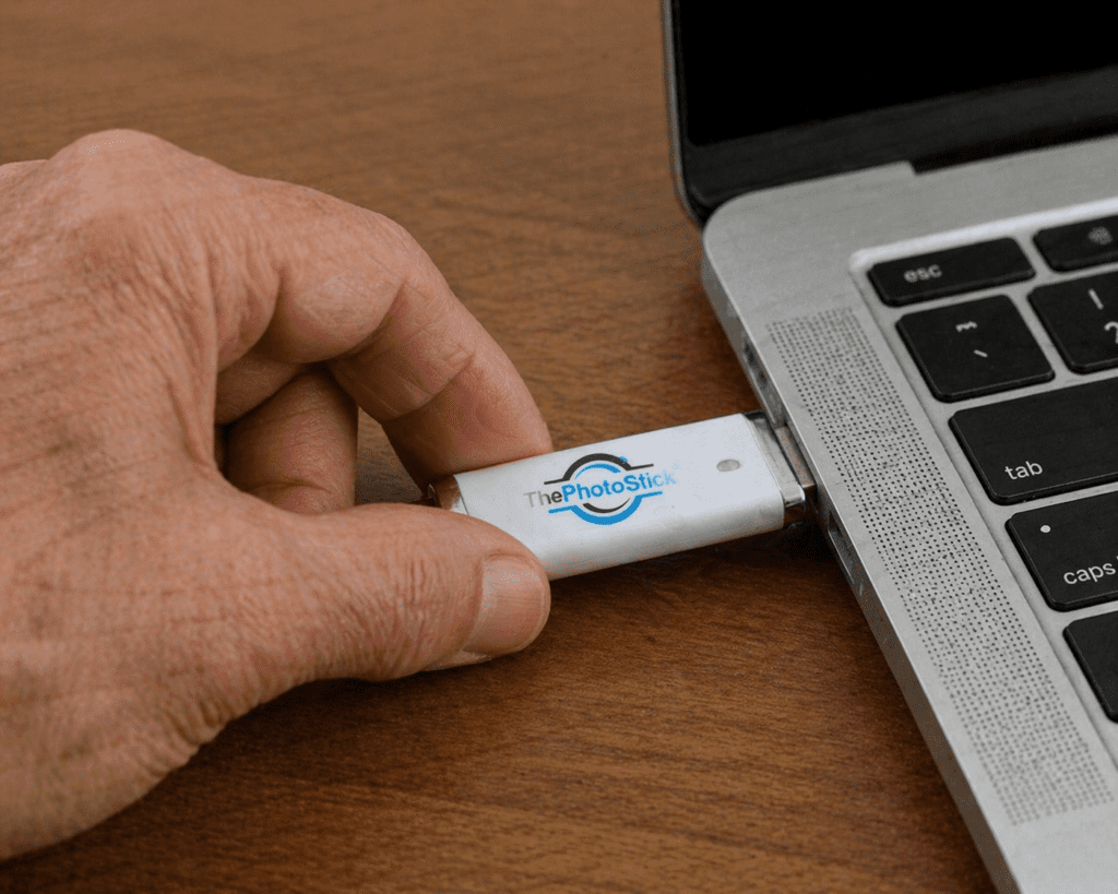 User testing ThePhotoStick review: Aged hand inserting the silver USB drive into a laptop port.